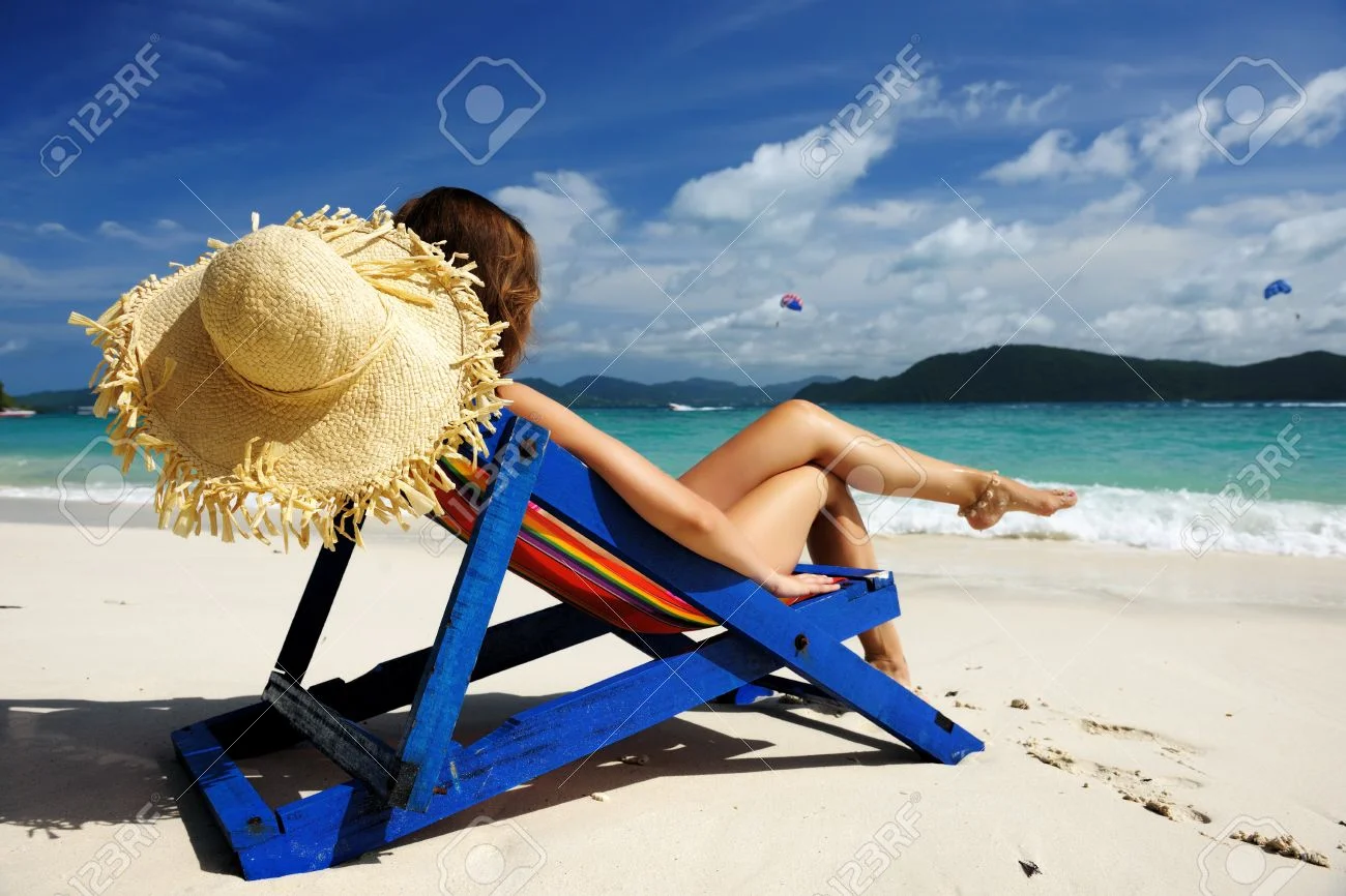 12398659-Girl-on-a-tropical-beach-in-chaise-lounge-Stock-Photo.webp