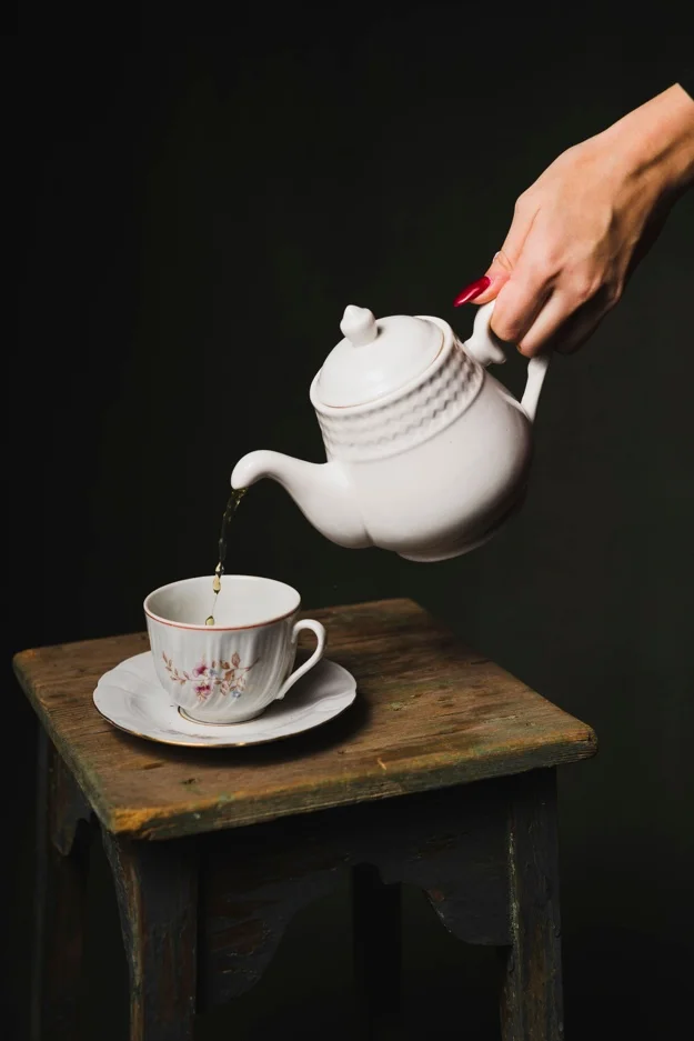 crop-hand-pouring-tea-into-cup_23-2147747242.webp