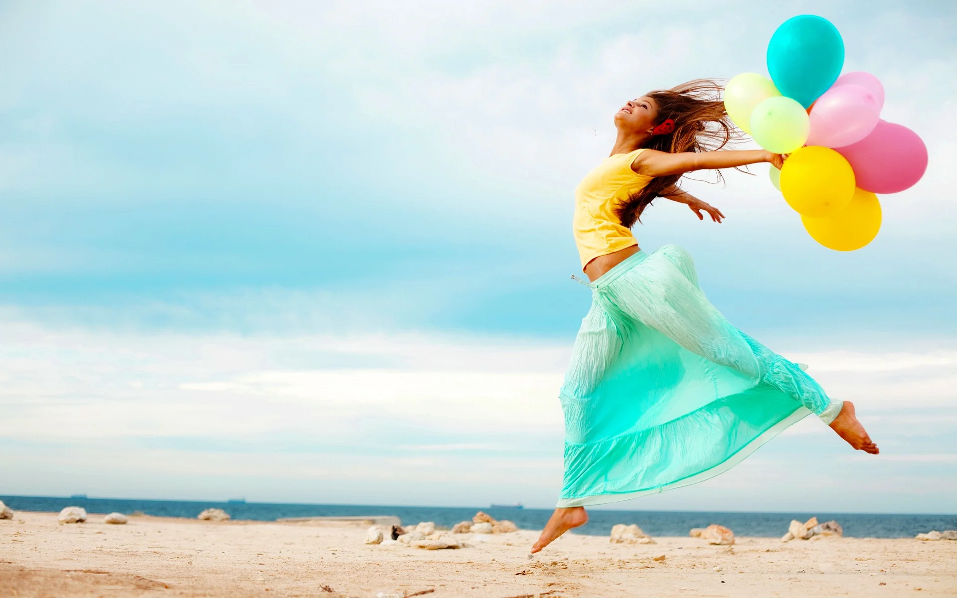 Happy-girl-at-beach-with-balloons.webp