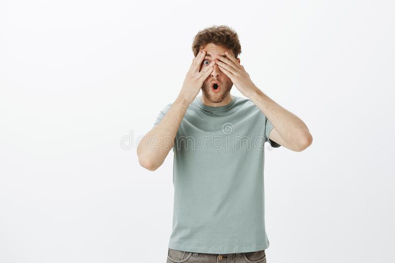 studio-shot-impressed-shocked-funny-man-blond-hair-closing-eyes-peeking-fingers-dropping-jaw-s...jpg