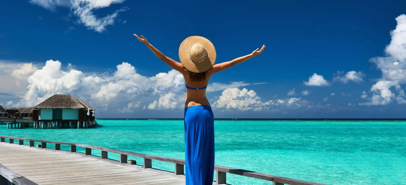 woman-on-a-tropical-beach-jetty-at-maldives-1452531181-b6JI.webp
