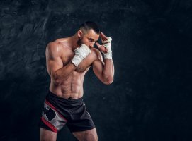 strong-muscular-fighter-is-showing-his-punch-while-posing-for-photographer-at-dark-photo-studi...jpg